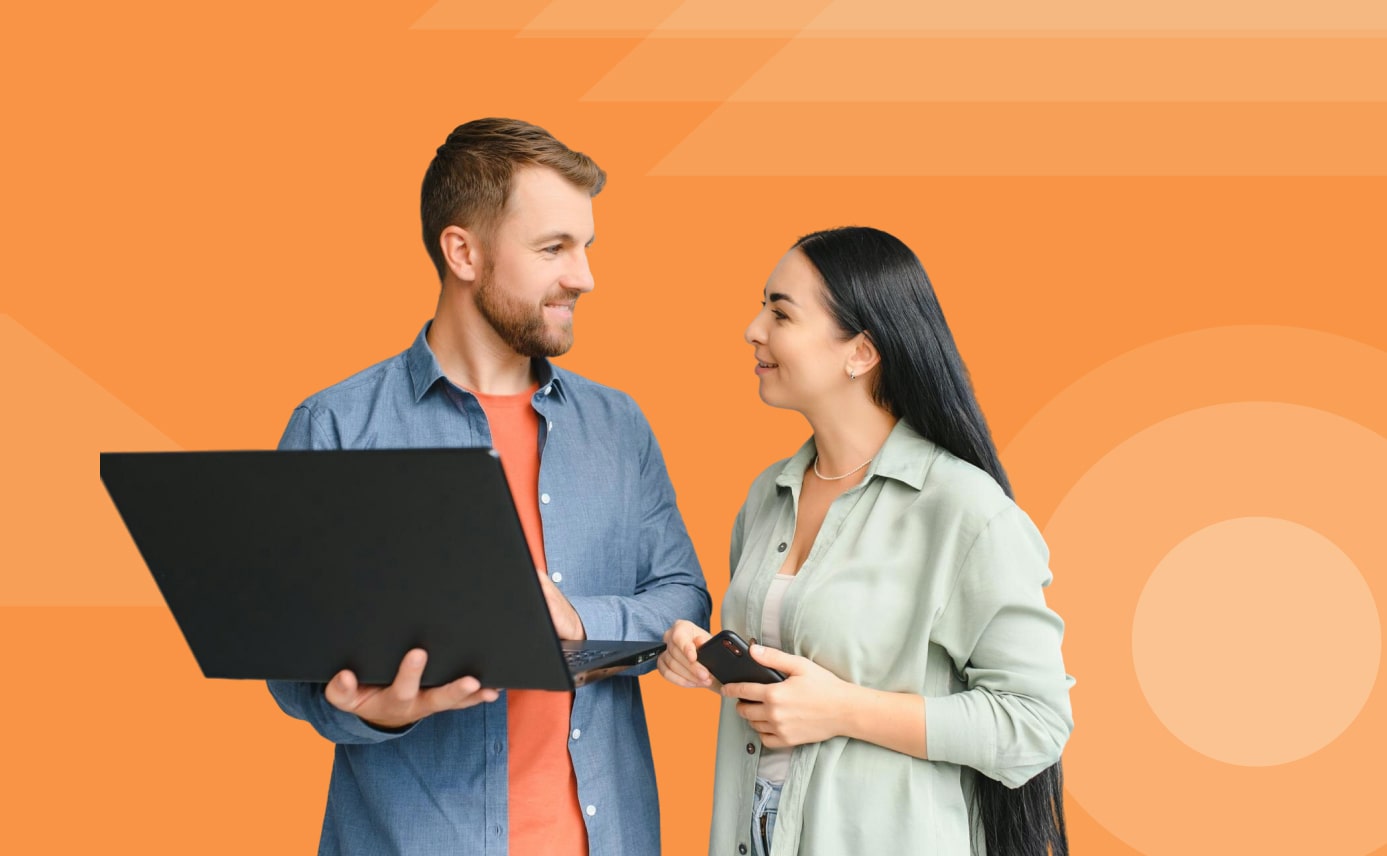Two team members discussing project work with a laptop and phone on an orange background