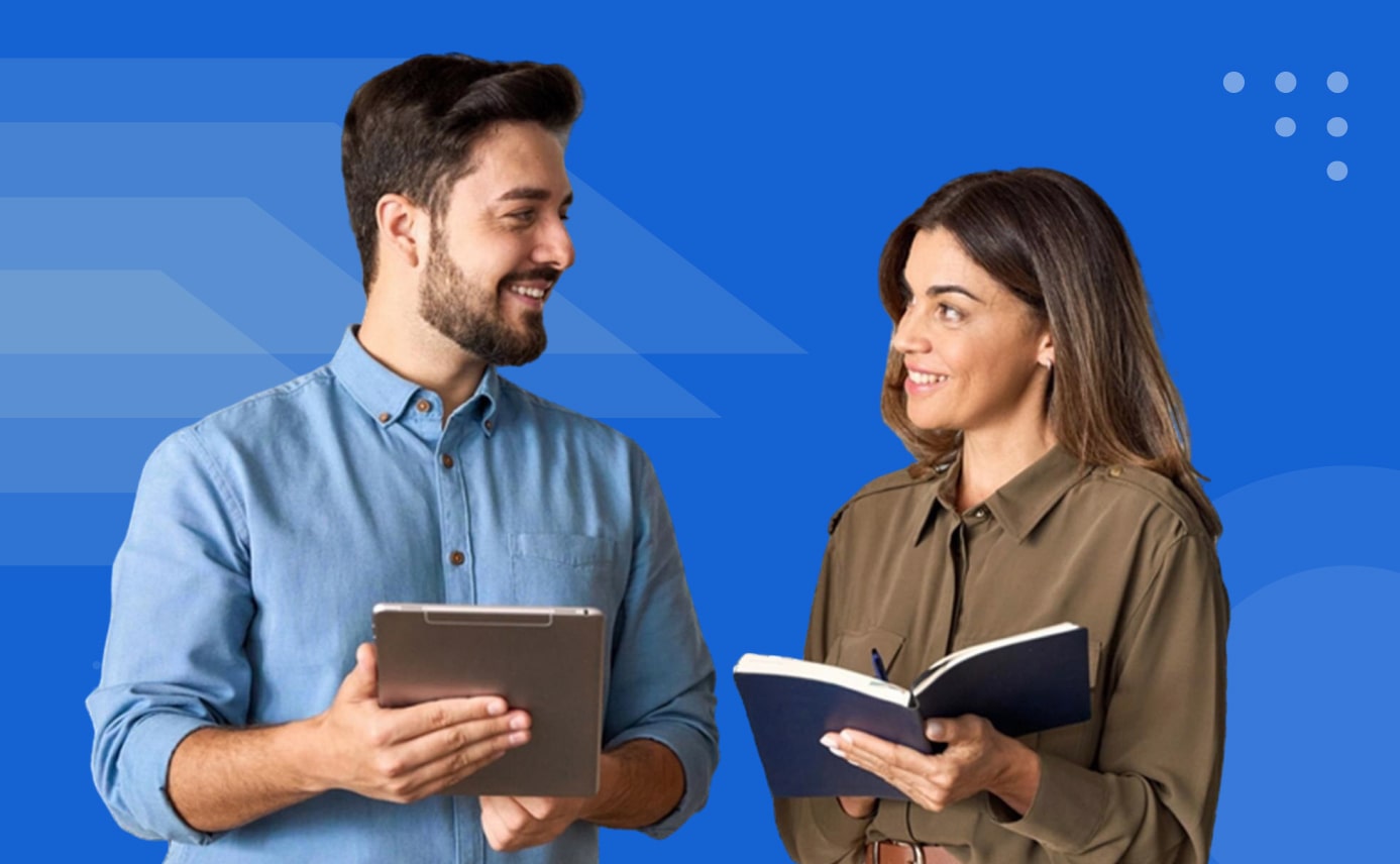 Two colleagues smiling while reviewing a tablet and notebook on a blue background
