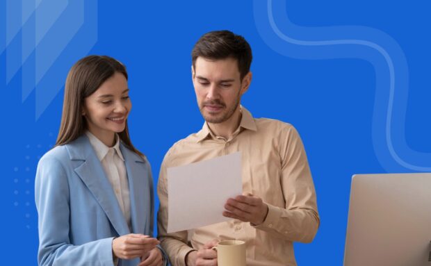 Two professionals reviewing a document near a computer with a blue background