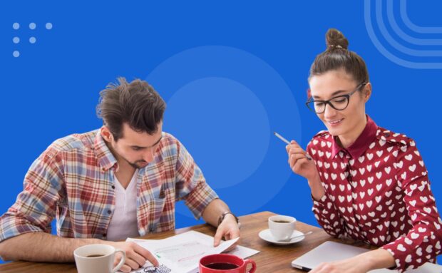 Two people collaborating at a table with documents, laptop, and coffee on a blue background