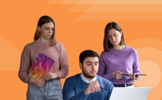 Three team members reviewing work on a laptop against an orange background